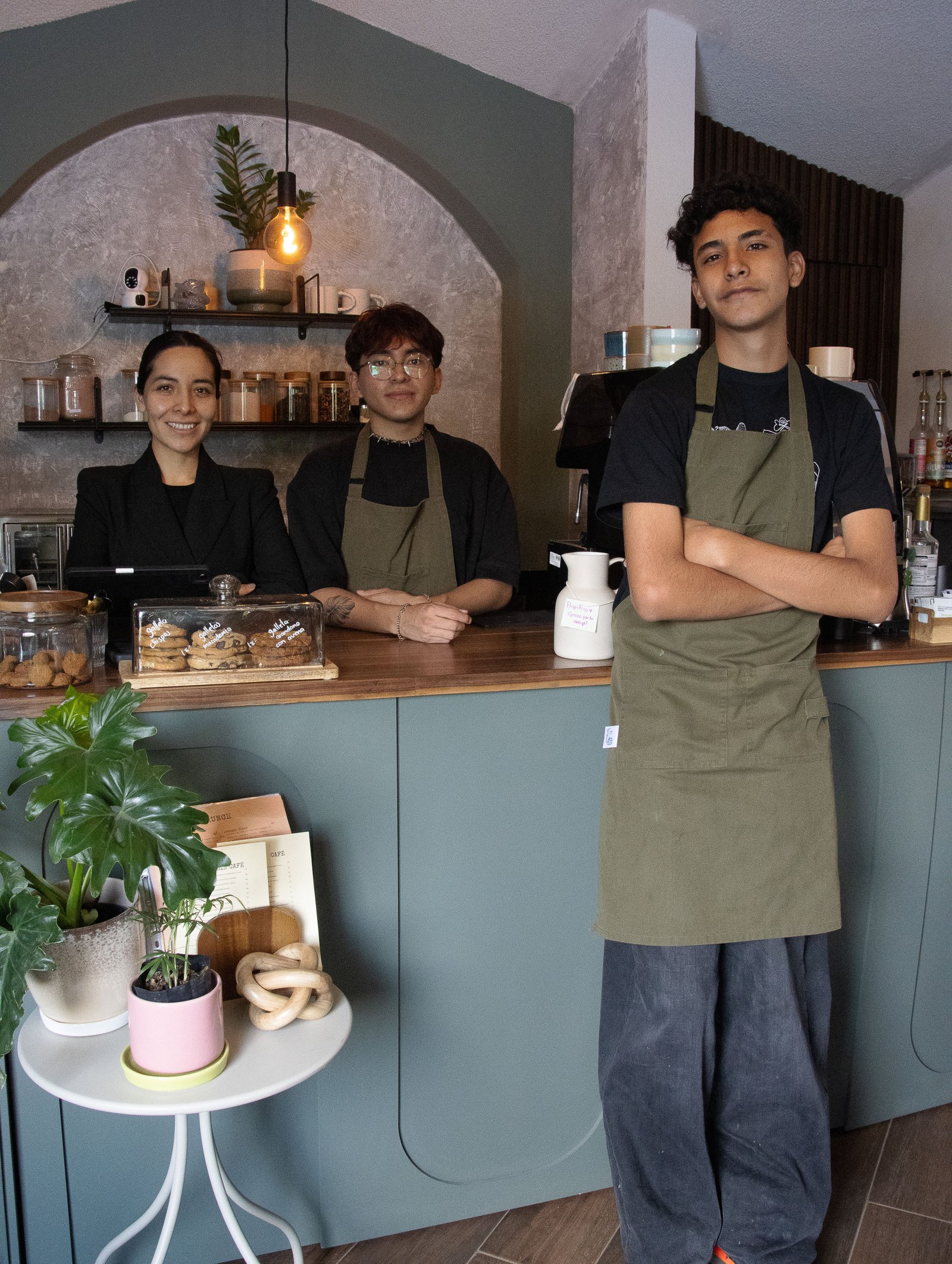 A customer smiling as a barista hands over a coffee in a sunlit café